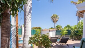 Un patio con suelo de baldosas, una planta en maceta, una piscina y mobiliario de exterior.