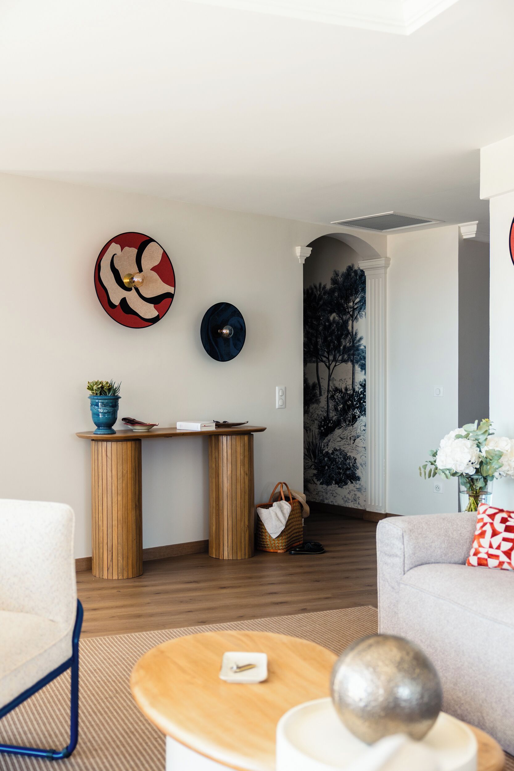A modern living room with a wooden coffee table, a white sofa, and a decorative wall piece.