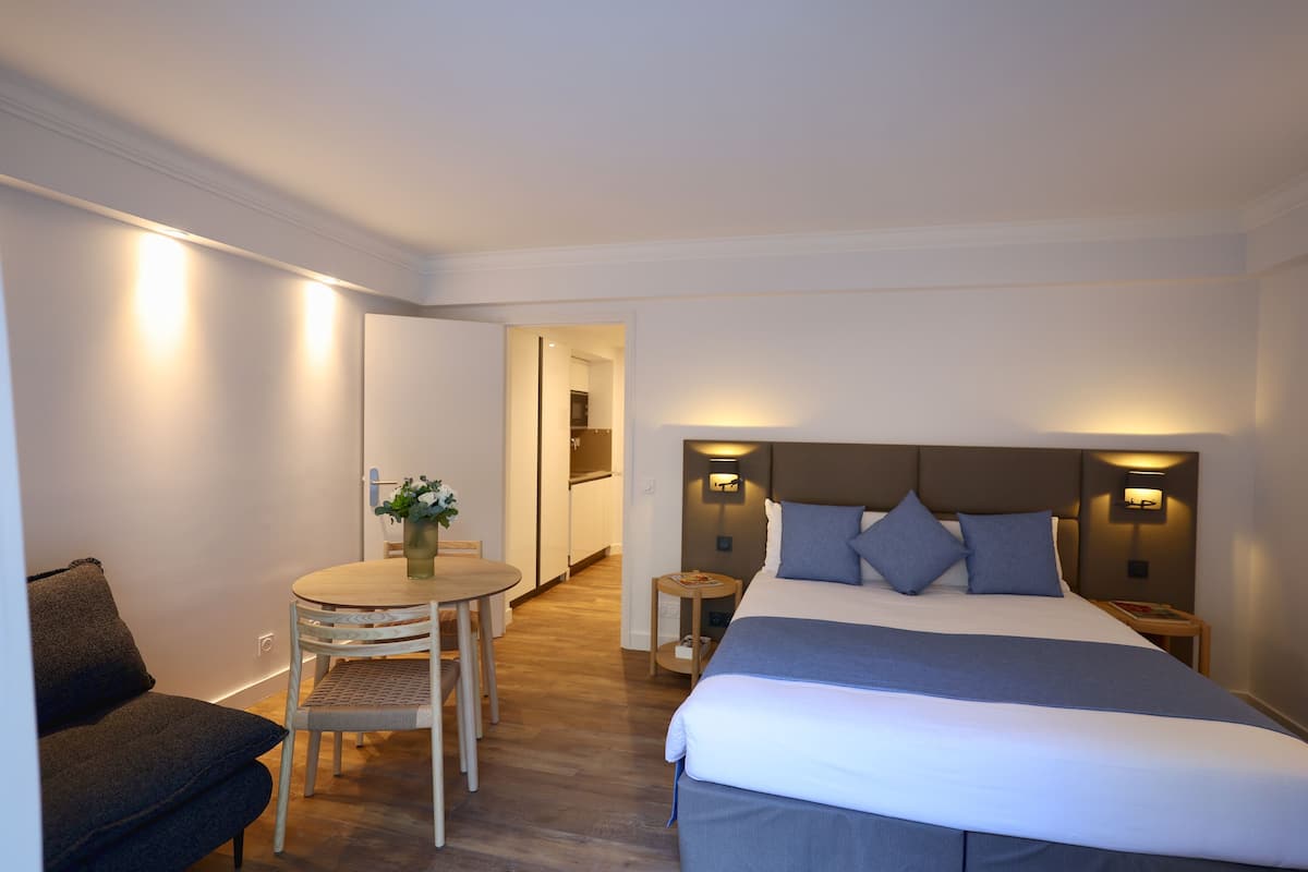 Quarto de hotel com uma cama, uma pequena mesa com uma cadeira e um sofá.