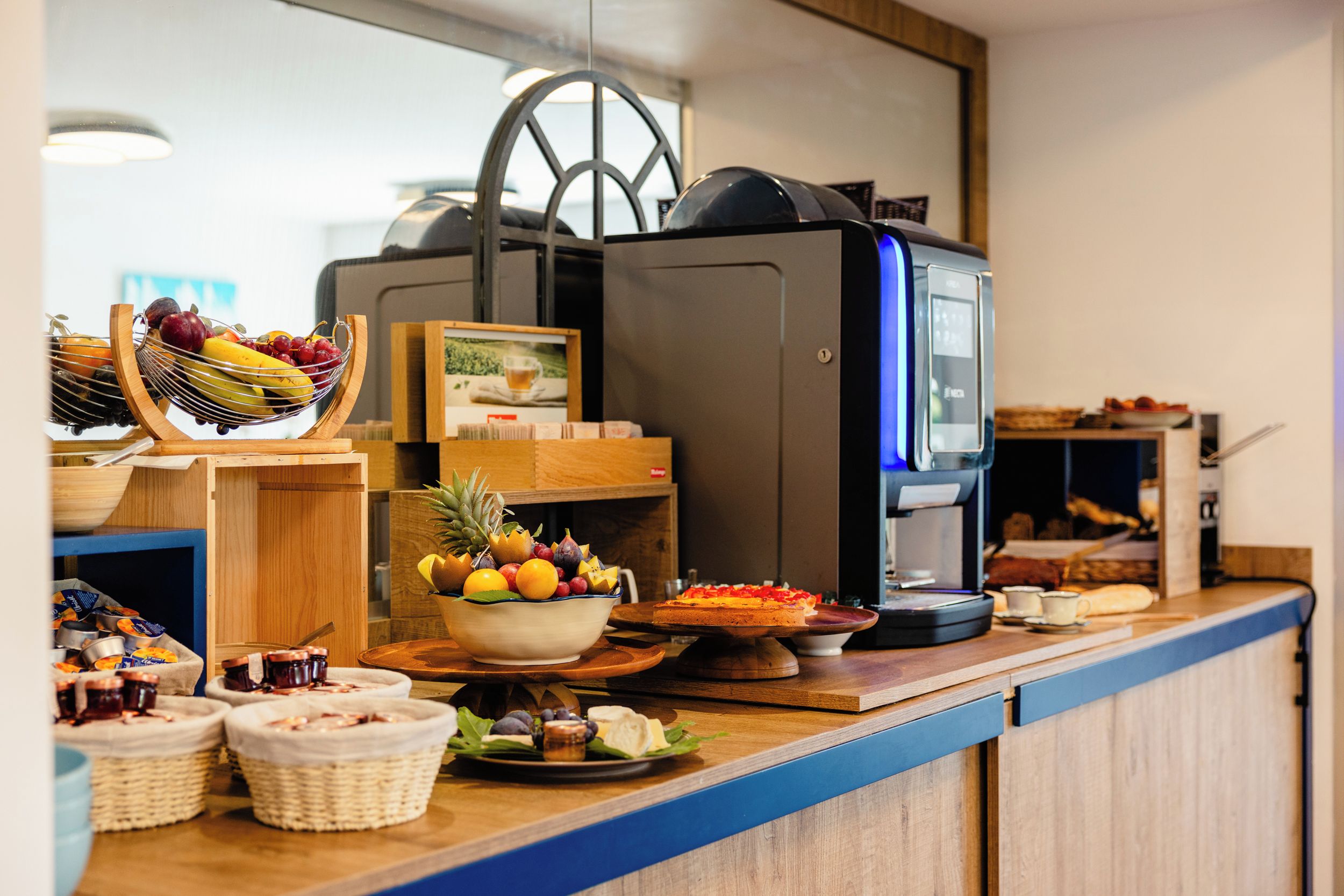 Montaje de bufé con una máquina de café, frutero y diversos alimentos.