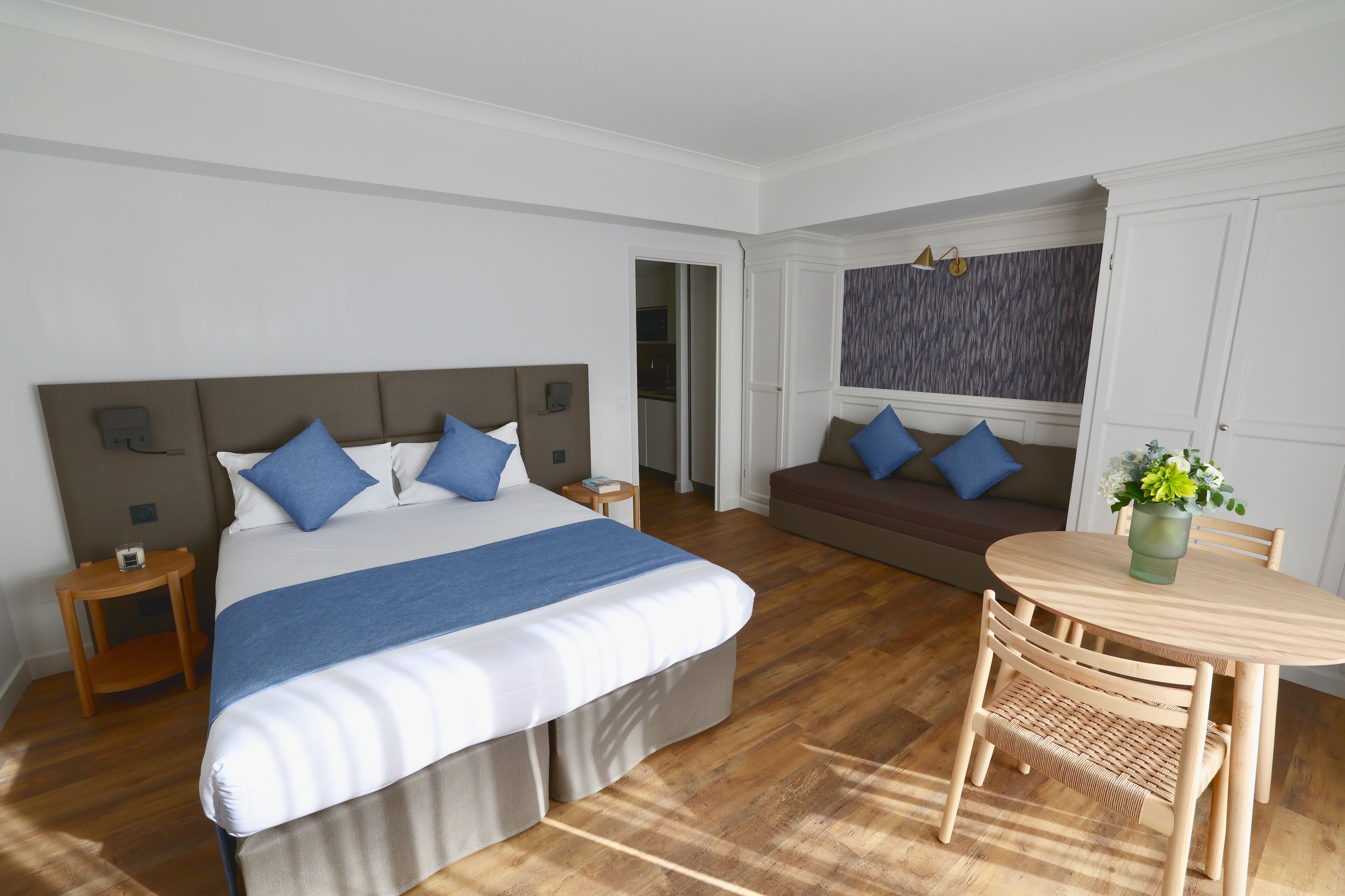 Ein Hotelzimmer mit einem großen Bett, einer Couch, einem Esstisch und einem kleinen Tisch mit einer Vase.
