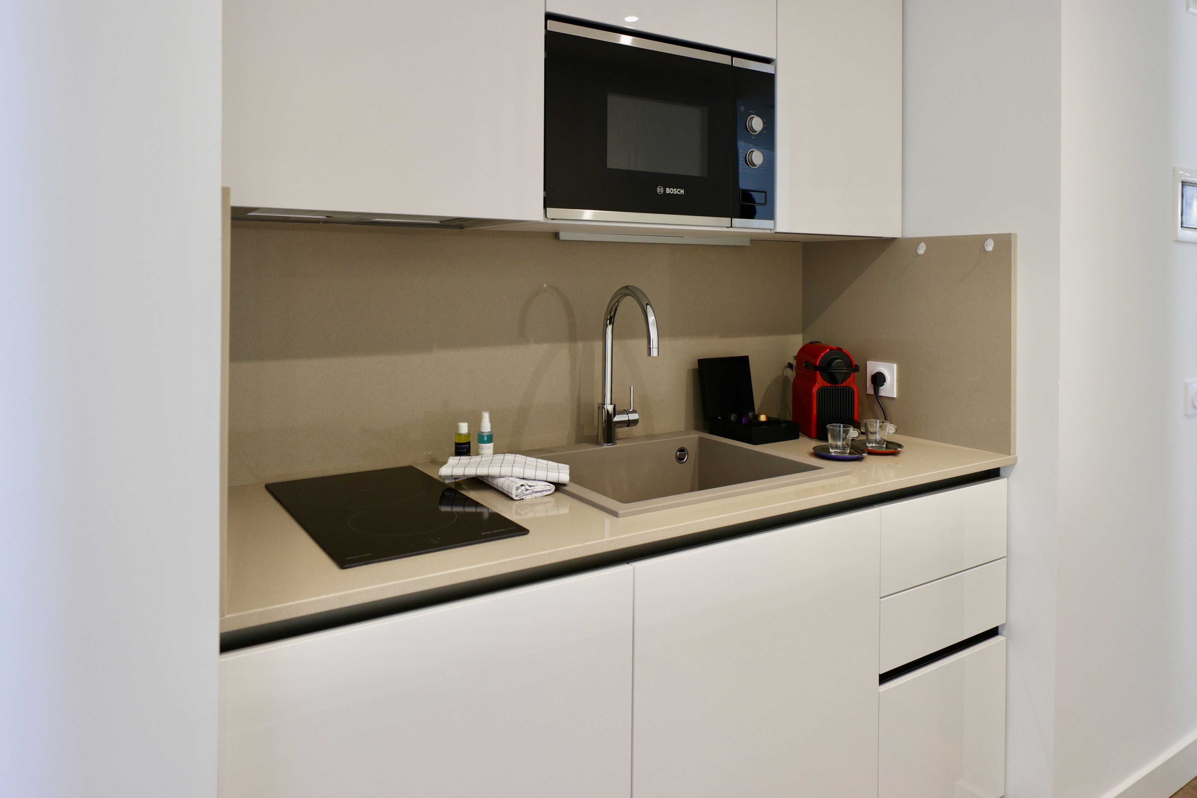 A modern kitchen with a Bosch microwave, a sink, and a coffee machine.