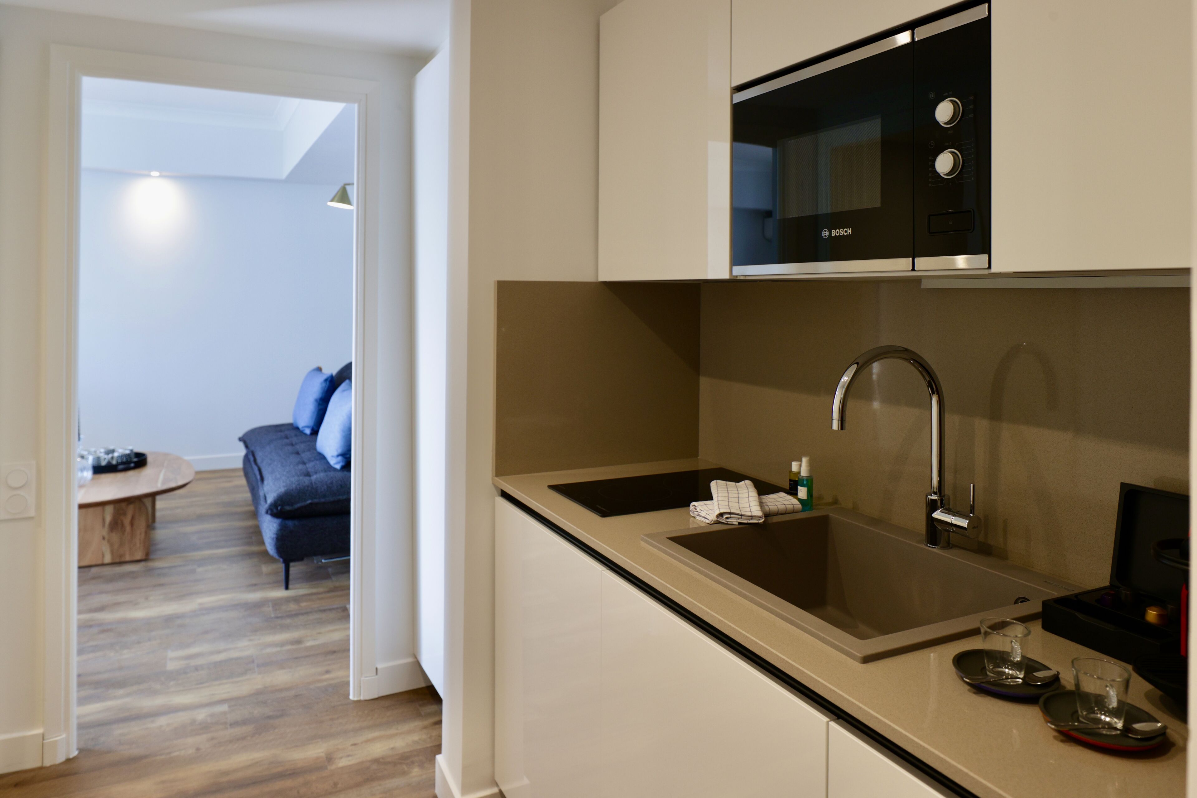 A modern kitchen with a Bosch microwave, stainless steel sink, and a small countertop area.