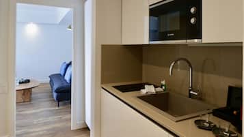 A modern kitchen with a Bosch microwave, stainless steel sink, and a small countertop area.