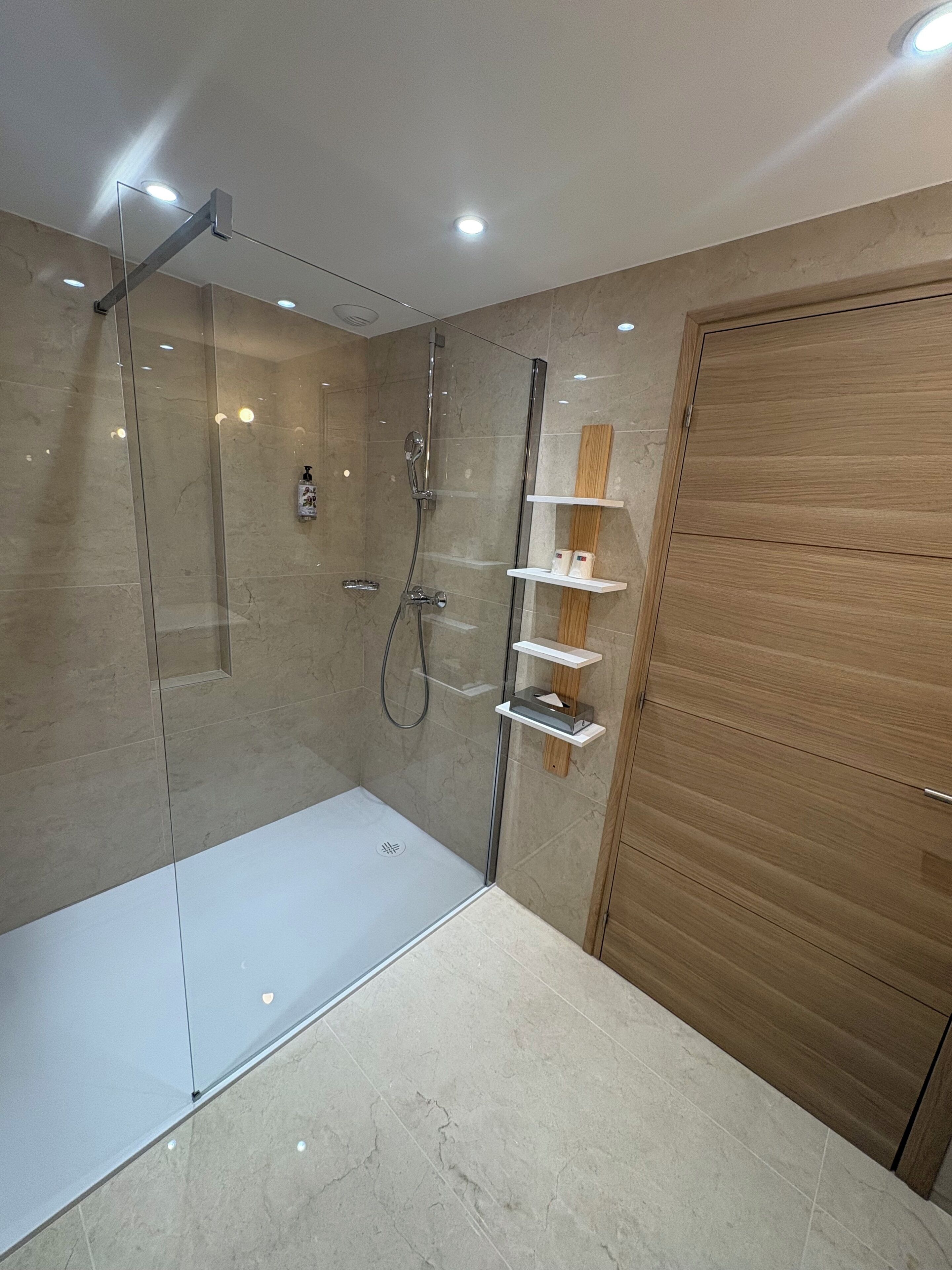 A modern bathroom with a glass-enclosed shower, a wooden vanity with a mirror, and a white sink.