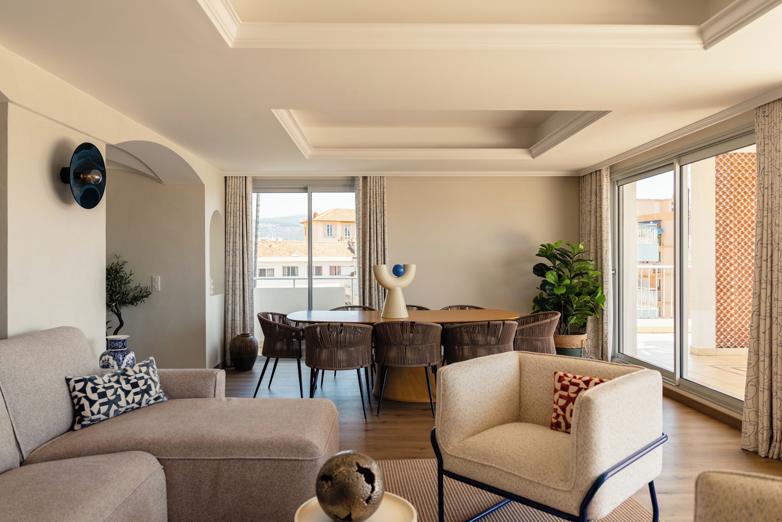 A modern living room with a sofa, armchair, dining table, and chairs.