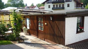 A building with a wooden facade, a door, and windows. - Vacation home with covered terrace No pets  (Friedrichroda)