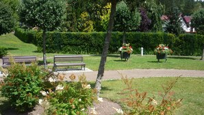 A park with a paved walkway, benches, and flower beds. - Vacation home with covered terrace No pets  (Friedrichroda)