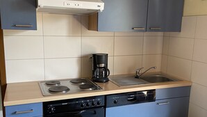 Una cocina compacta equipada con estufa, horno, lavavajillas y cafetera.