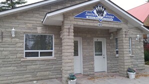 A stone building with a sign for 'Suites of Wasaga' indicating weekly rentals. - Suites of Wasaga Beach Area 2- mins walk Beach 1 (Wasaga Beach)