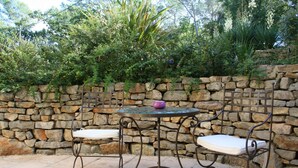 Un muro de piedra con una mesa metálica y dos sillas.