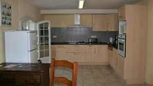 Una cocina compacta con armarios de madera clara, un refrigerador blanco, un microondas y una estufa.