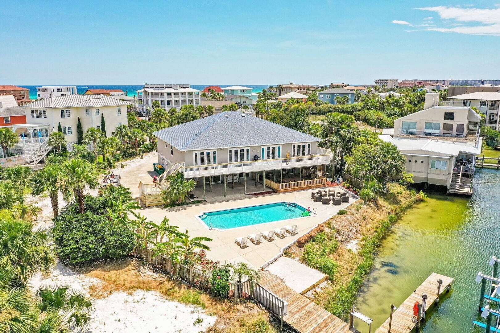 Une grande maison avec une piscine, entourée de palmiers et dotée d’un quai.