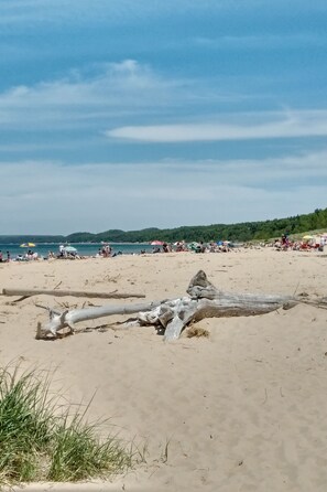 A sandy beach with people and colorful umbrellas.