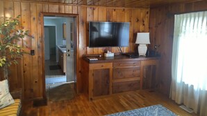 A wooden-paneled room with a television, a desk, and a lamp.