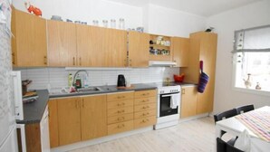 Una cocina compacta con armarios de madera, una estufa blanca y un pequeño comedor con mesa y sillas.