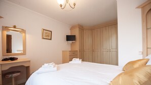 A hotel room with a large bed, a desk with a chair, a television, and wooden wardrobes. - Private detached 3 bedroom bungalow in Preston (Preston)