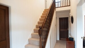 A staircase with wooden balusters and beige carpeted steps leading to a door. - Private detached 3 bedroom bungalow in Preston (Preston)