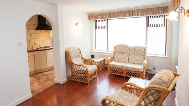 A spacious living area with a kitchen in the background, featuring wicker furniture and large windows. - Private detached 3 bedroom bungalow in Preston (Preston)