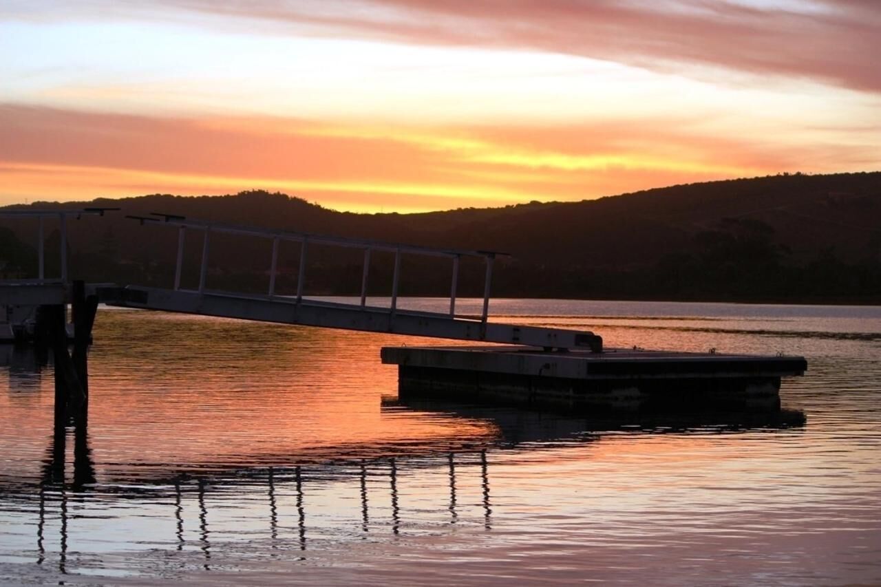 A pier extending into calm water with a sunset in the background.