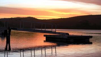 A pier extending into calm water with a sunset in the background.