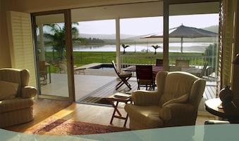 A spacious room with a large sliding glass door leading to an outdoor patio with a pool, chairs, and a table.