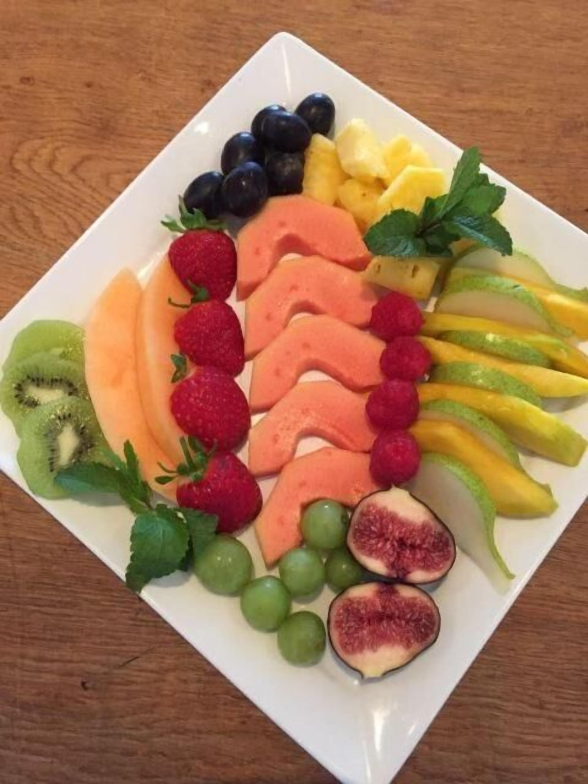 Um prato quadrado branco com várias frutas fatiadas dispostas de forma organizada.