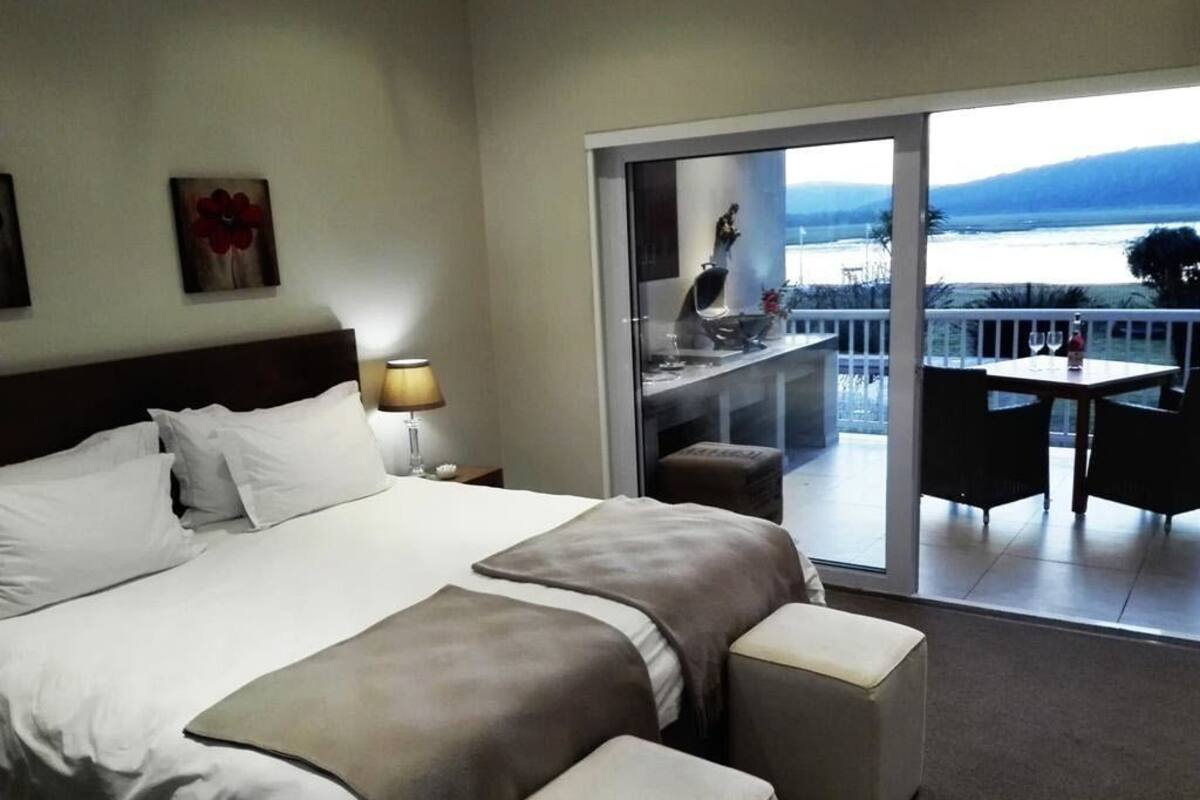 Ein Hotelzimmer mit einem großen Bett, einem Balkon mit Tisch und Stühlen sowie Meerblick.
