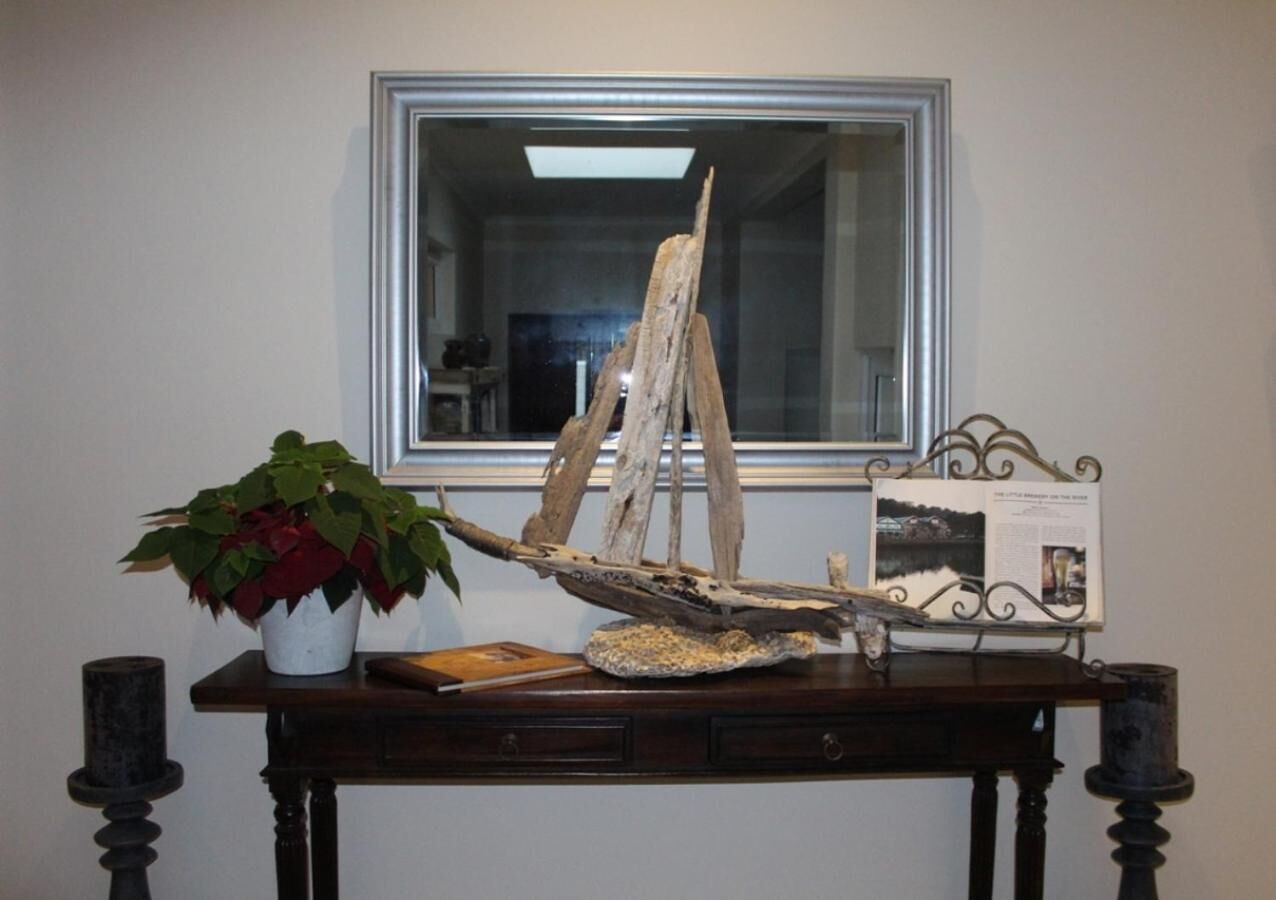 A wooden boat model on a table with a potted plant and a framed picture.