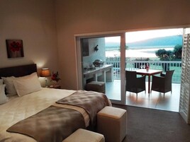 Habitación de hotel con cama, una mesita y un balcón con vistas al agua.