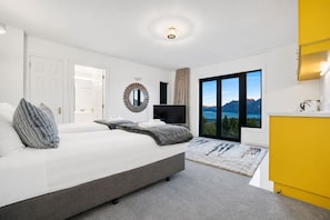A modern bedroom with a large bed, a television, and a view of a lake through a sliding door.