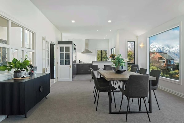 A modern kitchen with a dining area, large windows, and a view of mountains.