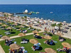 Um resort à beira-mar com espreguiçadeiras, guarda-sóis e área de piscina.