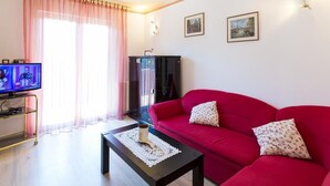 Ein Wohnzimmer mit einem roten Sofa, einem Couchtisch, einem Fernseher und einem Schrank.