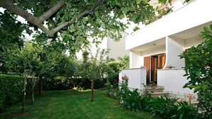 Ein modernes, zweistöckiges Haus mit gepflegtem Garten, einer Holztür und einer kleinen Außenlounge.