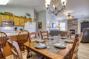 A dining area with a wooden table set for six, surrounded by wooden chairs.