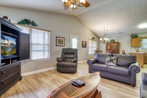 A living room with a television, leather chairs, a glass coffee table, and a dining area in the background. - Pigeon Forge One story 3 bedroom Creekside-Enjoy the sounds of the creek- Seasonal Pool Access (Pigeon Forge)