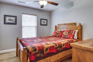 Ein Schlafzimmer mit einem Holzbett, einem Deckenventilator und zwei gerahmten Bildern an der Wand.