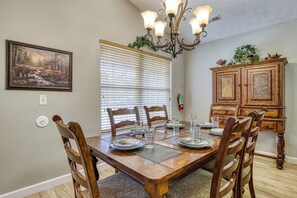 A dining room with a wooden table set for four, surrounded by chairs, a chandelier, a painting on the wall, and a cabinet with decorative items. - Pigeon Forge One story 3 bedroom Creekside-Enjoy the sounds of the creek- Seasonal Pool Access (Pigeon Forge)