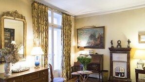 A traditional room with a wooden floor, a large mirror, a fireplace, and a painting on the wall.