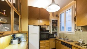 A compact kitchen with wooden cabinets, a white refrigerator, a black oven, a microwave, and a gas stove.