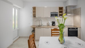 Una cocina moderna con microondas, cafetera y horno. Hay una mesa de comedor con un florero.
