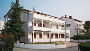 A multi-story residential building with balconies, a satellite dish, and a gated entrance.