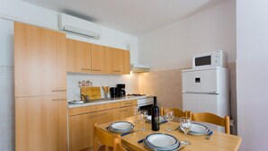 A compact kitchen with wooden cabinets, a gas stove, a coffee maker, and a microwave.