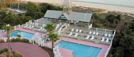 A resort with two swimming pools, a tennis court, and a beach view.