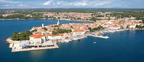 An aerial view of a coastal town with a prominent tower, waterfront buildings, and a marina.