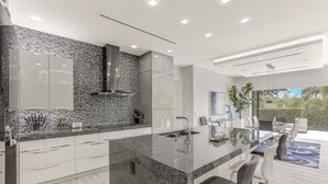 Una cocina moderna con encimera de granito, electrodomésticos de acero inoxidable y una isla grande con asientos tipo barra.