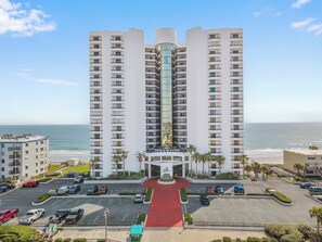 A high-rise hotel with multiple floors, a central courtyard, and a view of the ocean.