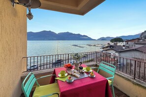 A balcony with a table set for two, overlooking a lake with boats and mountains in the background. - Residenza Menaggio - Mimosa (Menaggio)