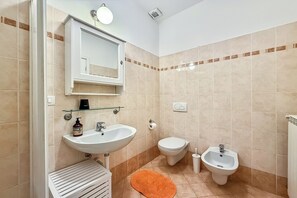 A bathroom with a sink, toilet, bidet, and a glass shelf above the sink. - Residenza Menaggio - Mimosa (Menaggio)